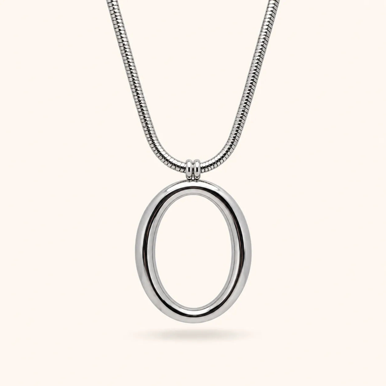 A silver snake chain necklace with a polished oval pendant, shown against a solid off-white background.